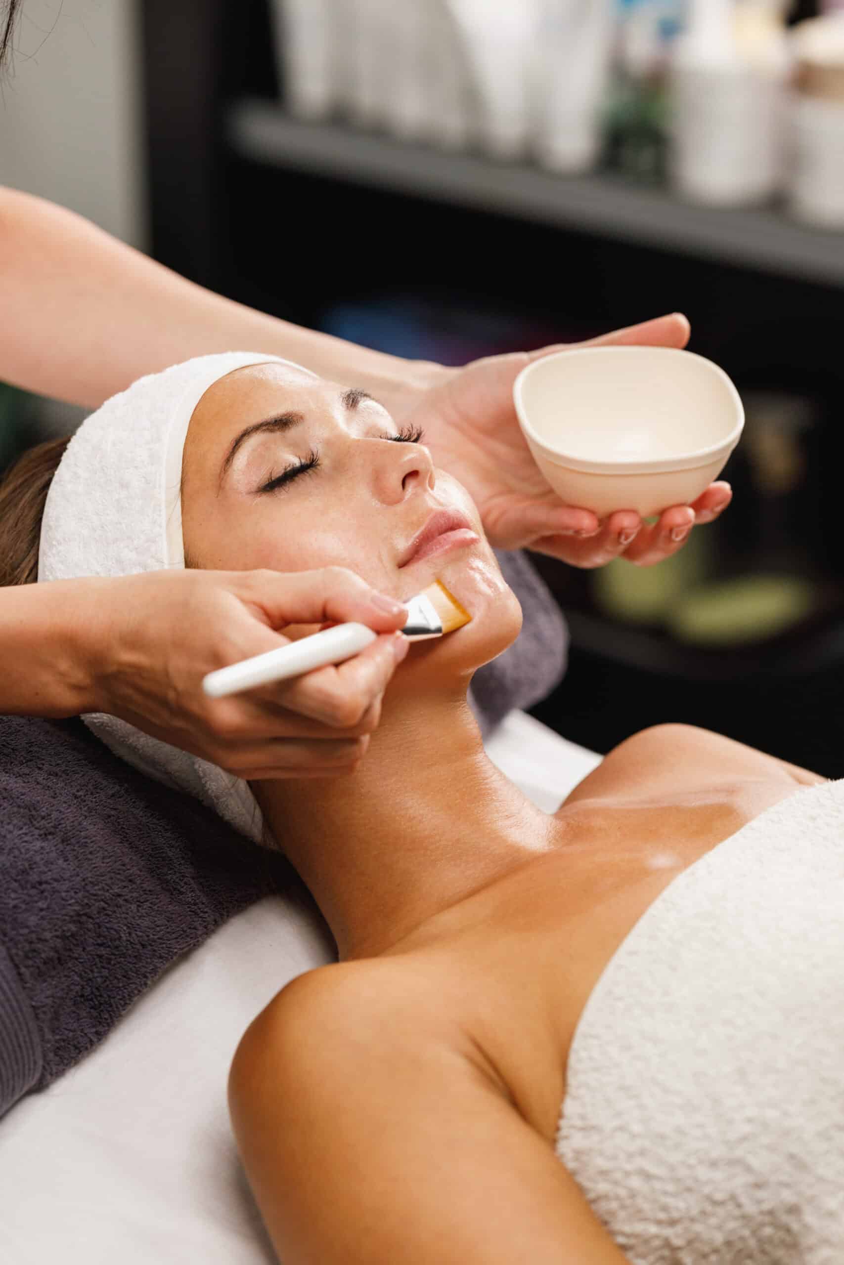 an esthetician brushing on a facial treatment