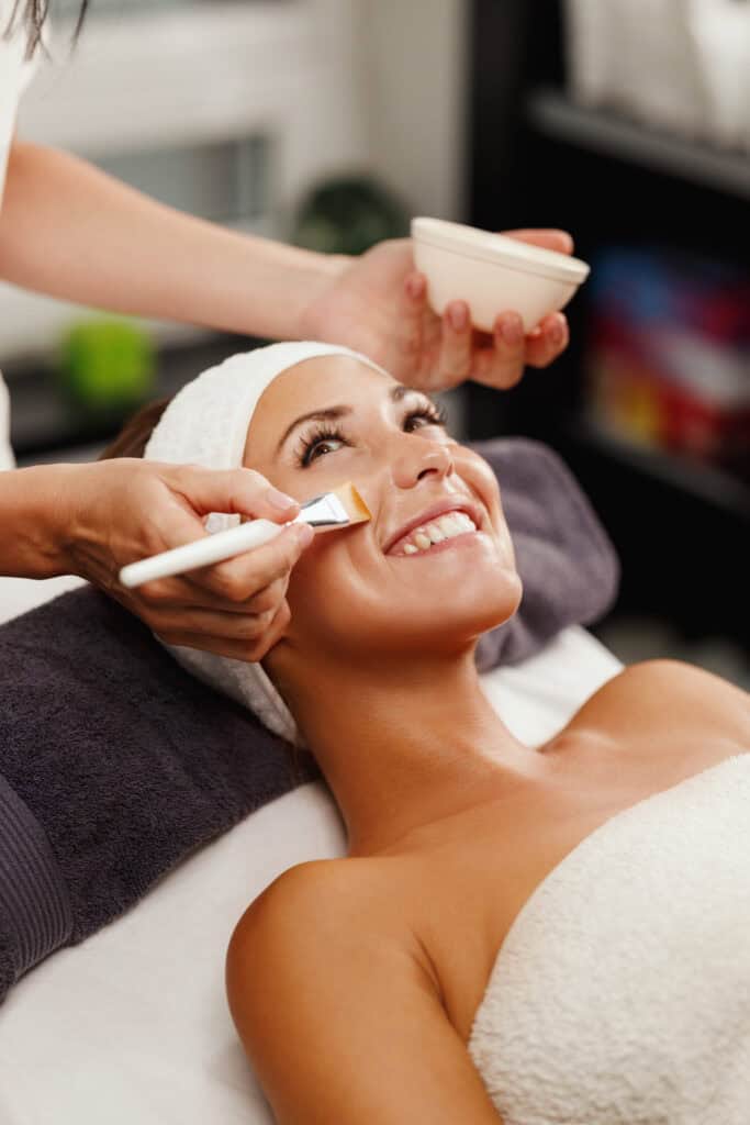 brushing a facial treatment on a smiling women's face