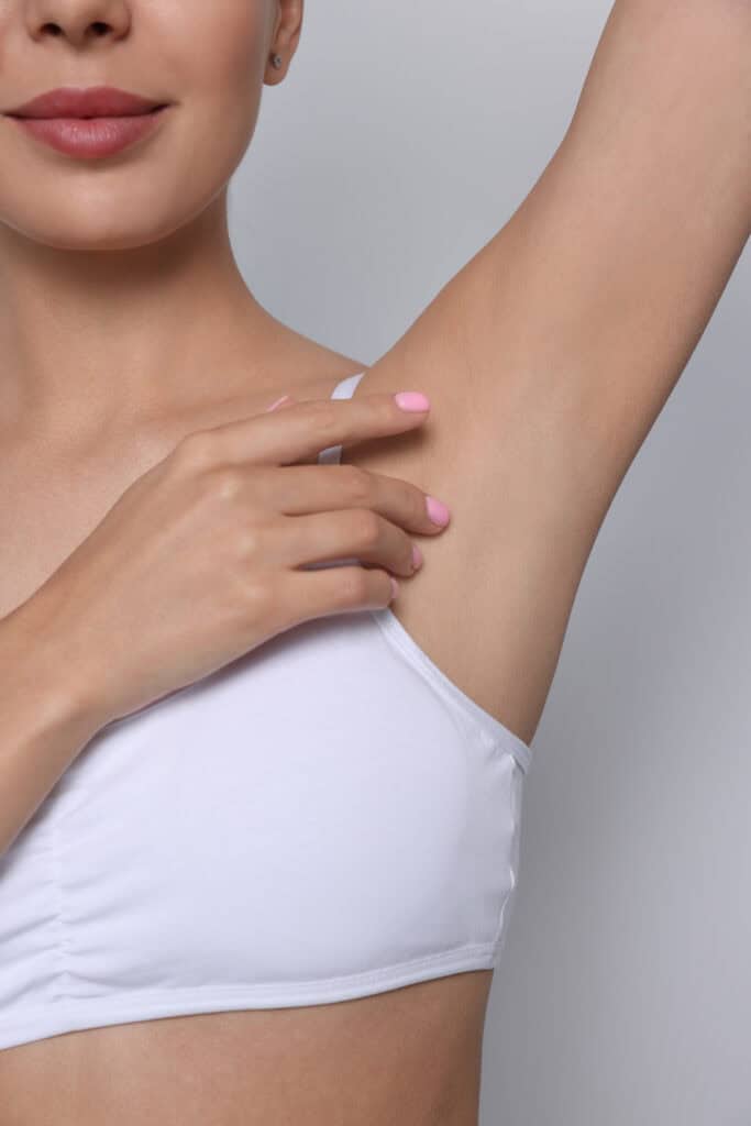 A woman extending her arm and pointing to her armpit
